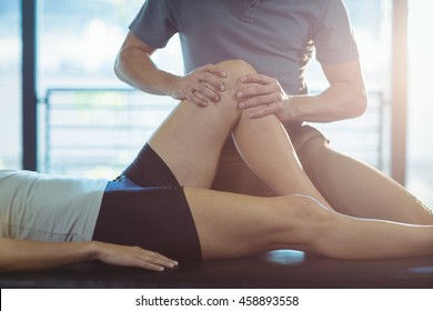 Physiotherapist giving knee therapy to a woman in clinic