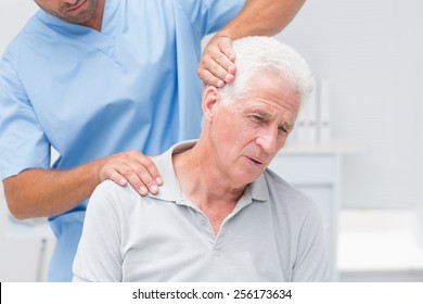 Physiotherapist giving physical therapy to senior male patient in clinic
