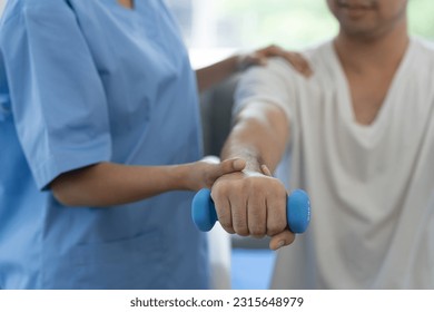 Physiotherapist giving therapy exercise with dumbbell equipment on male patient athlete arm and shoulder, physiotherapy concept, health insurance. - Powered by Shutterstock