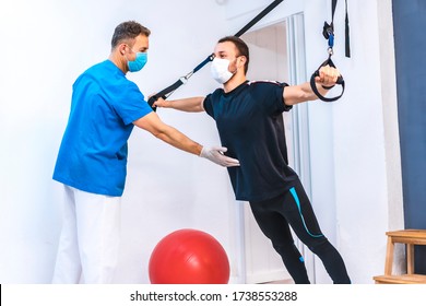 Physiotherapist helping a patient by stretching with rubber bands upside down. Physiotherapy with protective measures for the Coronavirus pandemic, COVID-19. Osteopathy, sports chiromassage