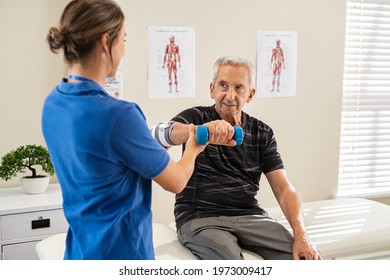 Physiotherapist helping senior man to lift hand weights. Senior man exercising and recovering at nursing home due to epicondylitis. Senior man exercising with professional physiotherapist. - Powered by Shutterstock