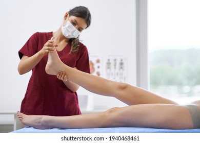 Physiotherapist In Mask Helping Female Patient