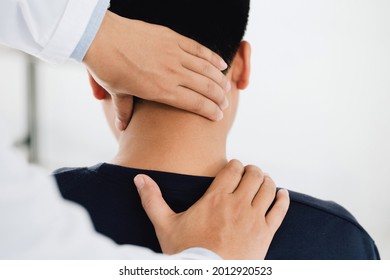 physiotherapist massage therapist holding male client's head and massaging tight neck muscles the result of prolonged use of mobile phones.Office Syndrome