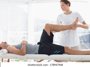 Physiotherapist massaging leg of young man at spa - Powered by Shutterstock