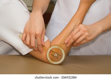 Physiotherapist Measuring Range Of Motion Patients' Elbow With Goniometer