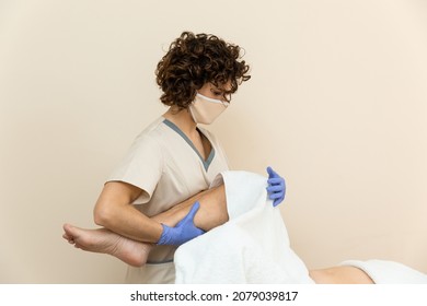 Physiotherapist Performing Leg Massage To Mature Woman