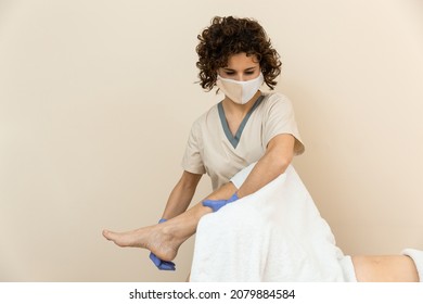 Physiotherapist Performing Leg Massage To Mature Woman With Towels