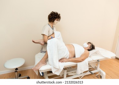 Physiotherapist Performing Leg Massage To Mature Woman With Towels