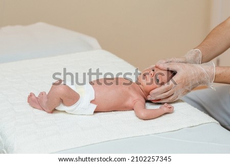 Physiotherapist performing a metopic suture work on a newborn baby in a therapy center.