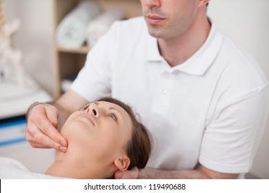 Physiotherapist pressing two fingers on the neck of his patient in a room
