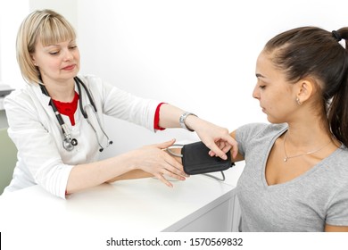 Physiotherapist puts on a medical tonometer to measure pressure on the patient arm.