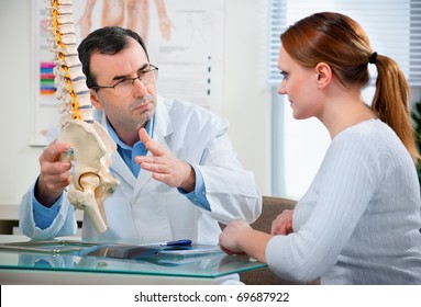 Physiotherapist shows the problem areas on the model of the spine to patient and explains the cause of her pain. - Powered by Shutterstock