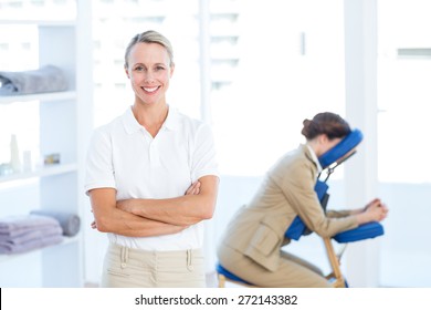 Physiotherapist smiling at camera arms crossed in medical office