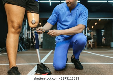 Physiotherapist take care patient and prosthetic leg of her. Physiotherapist helping disabled Woman with prosthetic leg in sports center. Rehab and gym with physiotherapists and patient work together - Powered by Shutterstock