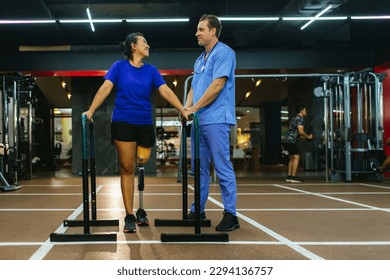 Physiotherapist take care patient and prosthetic leg of her. Physiotherapist helping disabled Woman with prosthetic leg in sports center. Rehab and gym with physiotherapists and patient work together - Powered by Shutterstock