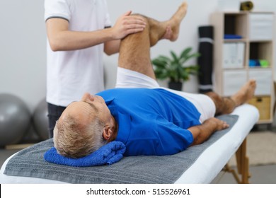 Physiotherapist working with an elderly patient doing mobility and functionality exercises with his left knee as he lies in an examination couch