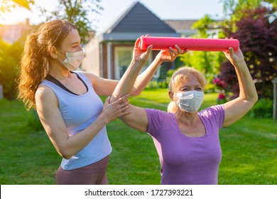 Physiotherapist Working With Elderly Patient Outdoors Both Wearing Medical Masks - Sport Exercises At Nursing Home With Assistant, Using Coronavirus Protection Measures After Or During Quarantine