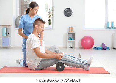 Physiotherapist working with young male patient in clinic - Powered by Shutterstock