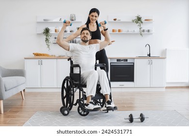 Physiotherapy healthcare, medical doctor consulting disabled caucasian patient. Nurse or wife helping mature man in wheelchair lifting arms with dumbbells for muscle strength in rehabilitation. - Powered by Shutterstock