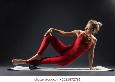 physiotherapy massage, woman with yoga roller on floor for leg tension on dark background, self massage with roller - Powered by Shutterstock