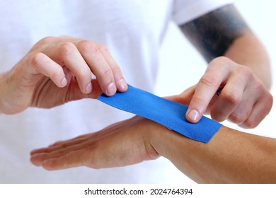 Physiotherapy Treatment With Therapeutic Kinesiology Tape For Wrist Pain, Aches And Tension. Prevention And Treatment In Competitive Sports. Hand With Kinesiology Tape.