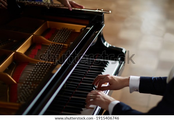 Pianist playing music on an old piano with an\
female transverse flute\
musician
