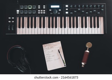 Piano keys, synthesizer on black background, music creation concept, flat lay.
