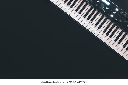 Piano keys, synthesizer on a black background, flat lay.