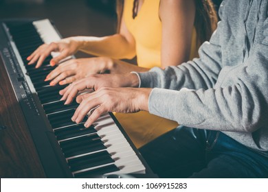 Piano players playing together four-handed piece during music school rehearsal 