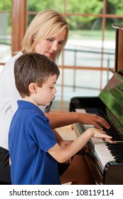 Piano Teacher Giving Lessons To A Young Boy