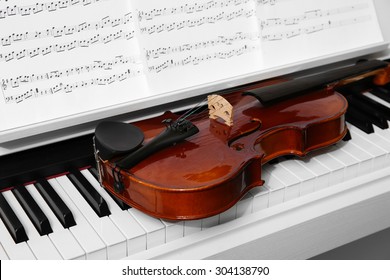 Piano with violin and music notes close up