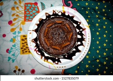 A Pic Of A Chocolate Kitkat Cake Plated With Chocolate Syrup In A Whote Dining.