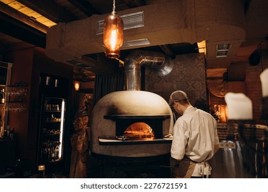 piceola stands near the wood-burning oven in the pizzeria. modern wood burning stove in a cafe.