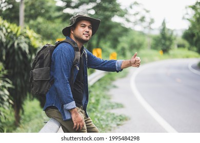 Pick me up. Man hitchhiking on the side of the road. Man try stop car thumb up. Hitchhiking one of cheapest ways traveling.