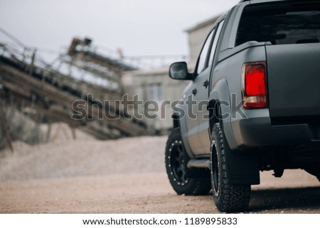 Pick up SUV car at the gravel carrier. Back view of the truck on the rural road. The army truck is stopped at the gravel. 