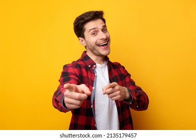 I Pick You. Portrait of excited young man pointing index fingers at camera, posing isolated over orange yellow studio background wall. Positive smiling adult male choosing and indicating