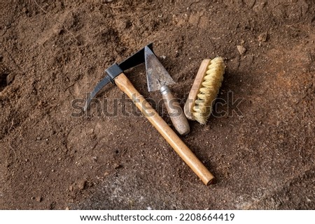 Pickaxe, trowel and brush. Tools in an archaeological excavation