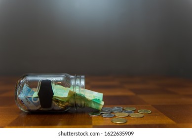 Pickering, Ontario/Canada - January 16 2020: Transparent Glass Jar With Money Inside On Top Of Wooden Table.  Concept For Swear Jar, Savings, Budgeting, Trip Fund.