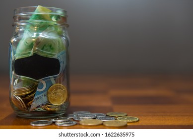 Pickering, Ontario/Canada - January 16 2020: Transparent Glass Jar With Money Inside On Top Of Wooden Table.  Concept For Swear Jar, Savings, Budgeting, Trip Fund.