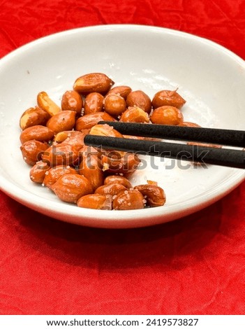 Picking Complimentary salted peanuts with chopsticks in a chinese restaurant on red background.copy space.