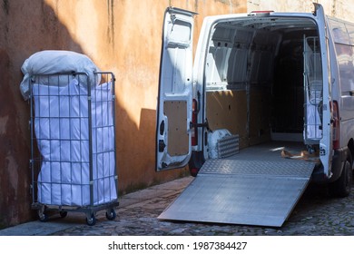Picking dirt laundry carts. The van equipped with lift ramp is parked in an old town city