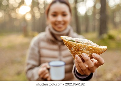 Picking Season, Leisure And People Concept - Close Up Of Young Asian Woman Drinking Tea And Eating Sandwich In Autumn Forest