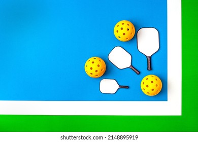 피클볼 디스플레이  블루그린 코트 배경에 세 개의 미니 패들이 있는 노란색 픽볼 3개. 스톡 사진