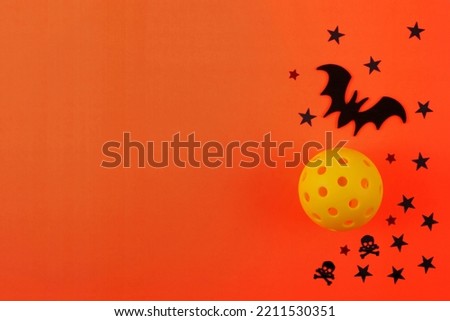 Pickleball Halloween with orange background, Yellow Pickleball, Black Bat and Stars.  Lots of room for text.