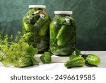 Pickled cucumbers in a jar with garlic and dill on the kitchen table, village harvest, homemade pickling recipe, cucumbers and ingredients for pickling, home canning concept,