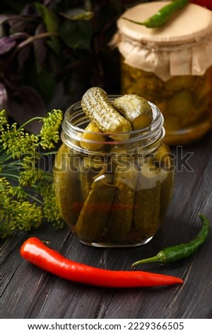 Pickled cucumbers in a jars on a dark wooden background. Homemade marinated cucumbers. Pickled cucumber salad in a jar.