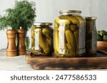 Pickled cucumbers in jars on grey table