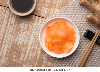 Pickled ginger in white plate and fresh root ginger and chopsticks on wooden table.Top view - Powered by Shutterstock