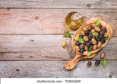 Pickled green and black Mediterranean olives and virgin olive oil in bottle over wooden background, top view - Powered by Shutterstock
