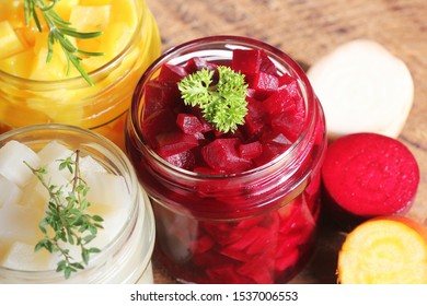 Pickled red, white, orange beet in glass jars. Variety pickles on rustic background .